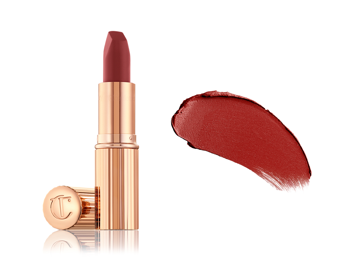 An open berry-rose lipstick in a gold colour-scheme with its lid next to it along with its swatch on the right side. 