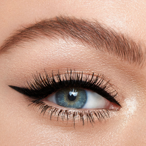Single eye close-up of a fair-tone model with blue eyes wearing a duo eyeliner in black and champagne-beige on her upper lid and lower waterline. 