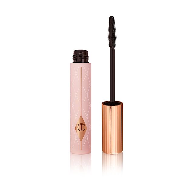Mascara in a pink-coloured tube with its gold-coloured lid with a black applicator next to it. 
