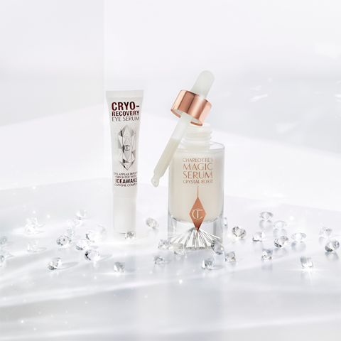 Eye serum in a white-coloured tube with geometric patterns on the front in a reflective, silver colour along with luminous, facial serum in a glass bottle with a white and gold dropper lid.