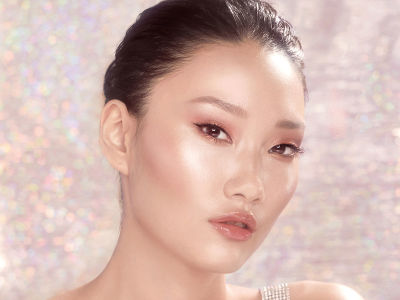 A fair-tone model with flawless skin wearing glowy, nude pink makeup with glossy pink lips. 