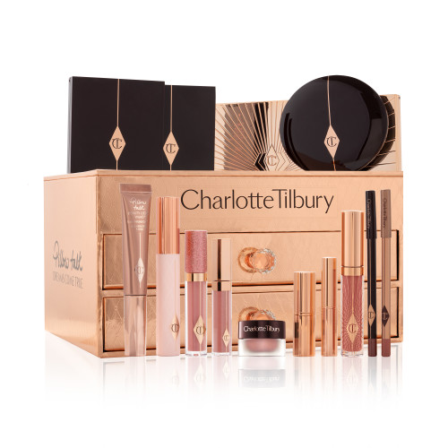 A reflective, gold-coloured chest with two drawers containing makeup items, which include Liquid highlighter wand in rose gold, black mascara, shimmery lip gloss in nude pink, glitter-free but high-shine lip gloss in nude pink, rose gold eyeshadow pigment in a petite pot, two closed lipsticks, travel-size lip gloss in nude pink, eyeliner pencil in dark brown, lip liner pencil in nude pink, quad eyeshadow palettes, 12-pan eyeshadow palette, and two-tone blush compacts.