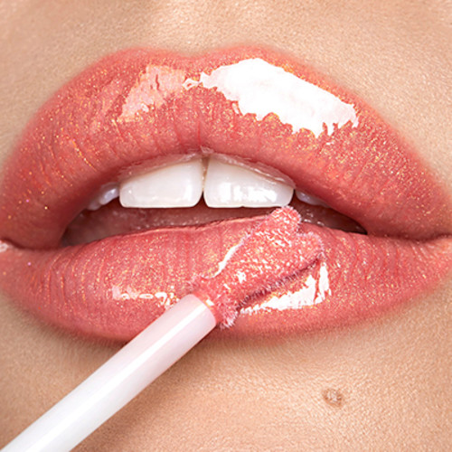 Lips close-up of a fair-tone model applying a high-shine lip gloss in a pinkish peach shade.
