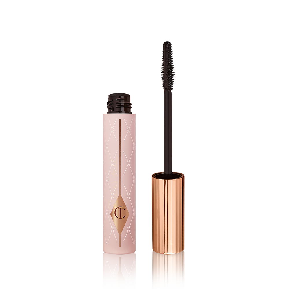 Mascara in a pink-coloured tube with its gold-coloured lid with a black applicator next to it. 