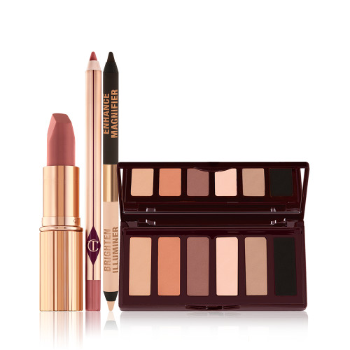 An open matte lipstick in a gold-coloured tube, lip liner pencil, double-ended eyeliner pencil in black and nude beige shades, and an open, mirrored-lid six-pan eyeshadow palette with matte eyeshadows in brown, peach, and beige shades.