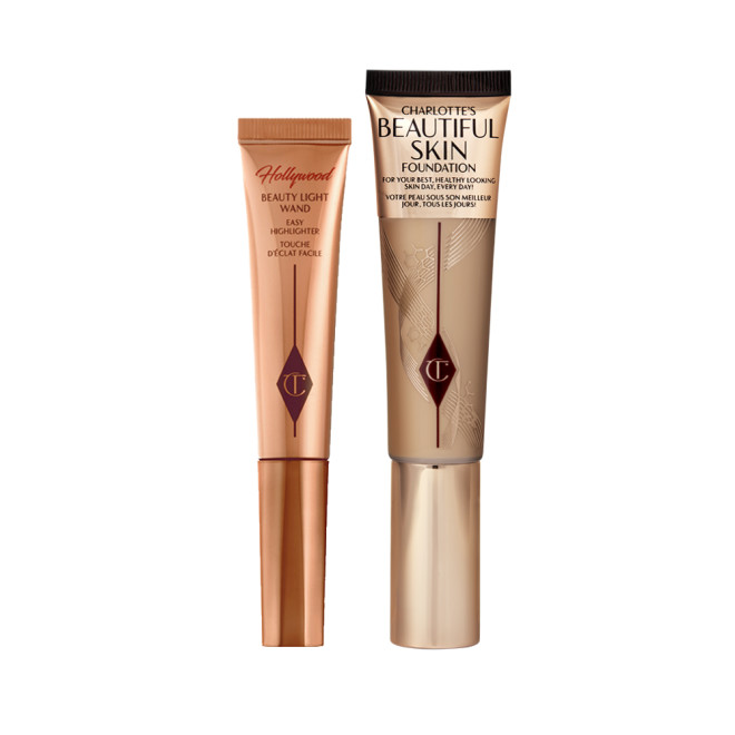 Highlighter wand in light gold-coloured packaging with a foundation wand in gold packaging with a ashy brown-beige-coloured body to show the shade of the foundation inside, and a gold-coloured lid.