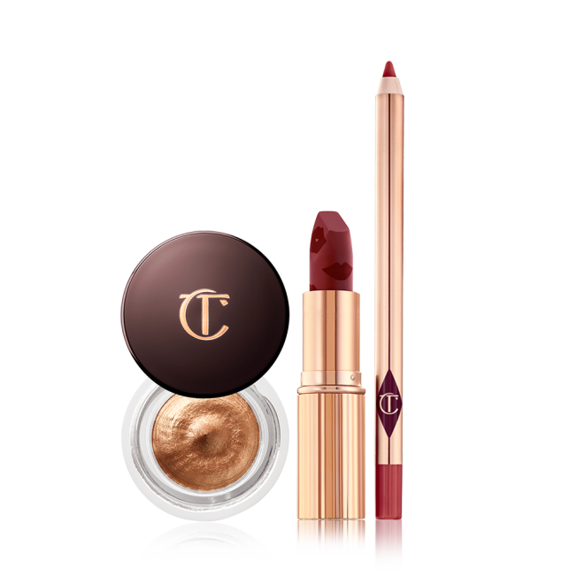 An open matte lipstick in a winter berry shade, lip liner pencil in a berry rose pink shade, and cream eyeshadow in a glass pot in an amber gold shade.