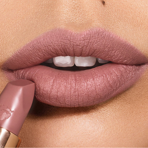 Lips close-up of a light-tone model applying a matte lipstick in a taupe nude shade,