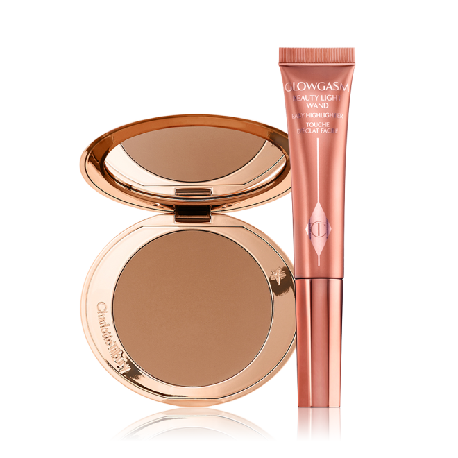 An open, mirrored-lid bonzer compact with a warm-brown bronzer and a highlighter-blush wand in a warm pink shade. 