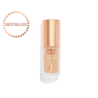 A closed glow-boosting primer in a glass bottle with a rose gold-coloured lid. 