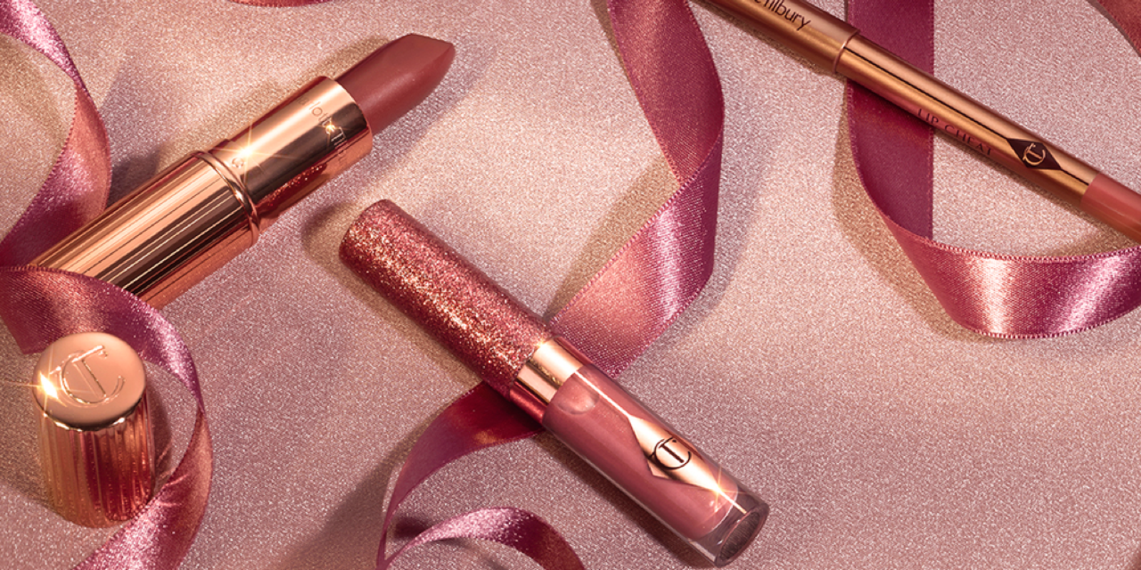 An open nude pink matte lipstick in a gold-coloured tube with shimmery nude pink lipstick, and a lip liner pencil in a nude pink shade. 