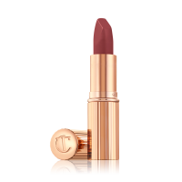 Opened, berry-pink lipstick in a metallic, golden case with its lid that's embossed with CT placed next to it. 