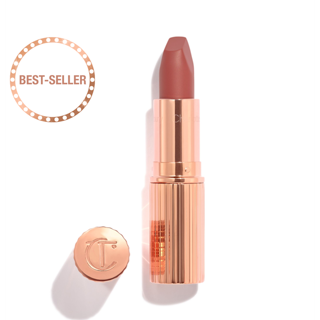Rouge à lèvres Matte Revolution en Pillow Talk Medium avec le capuchon retiré Ouvert, le rouge à lèvres rose framboise se trouve dans un étui métallique et doré avec son bouchon embossé des lettres CT placé à côté.