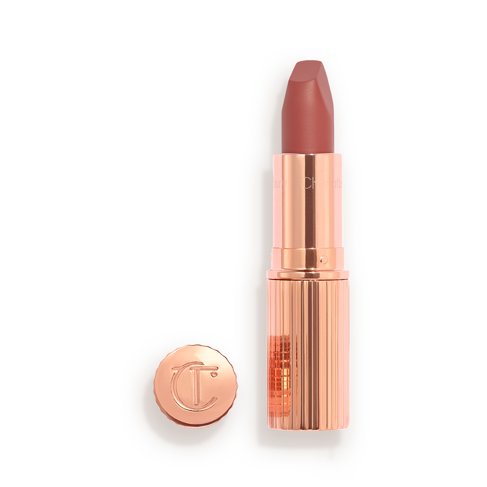 Opened, berry-pink lipstick in a metallic, golden case with its lid that&#x27;s embossed with CT placed next to it. 