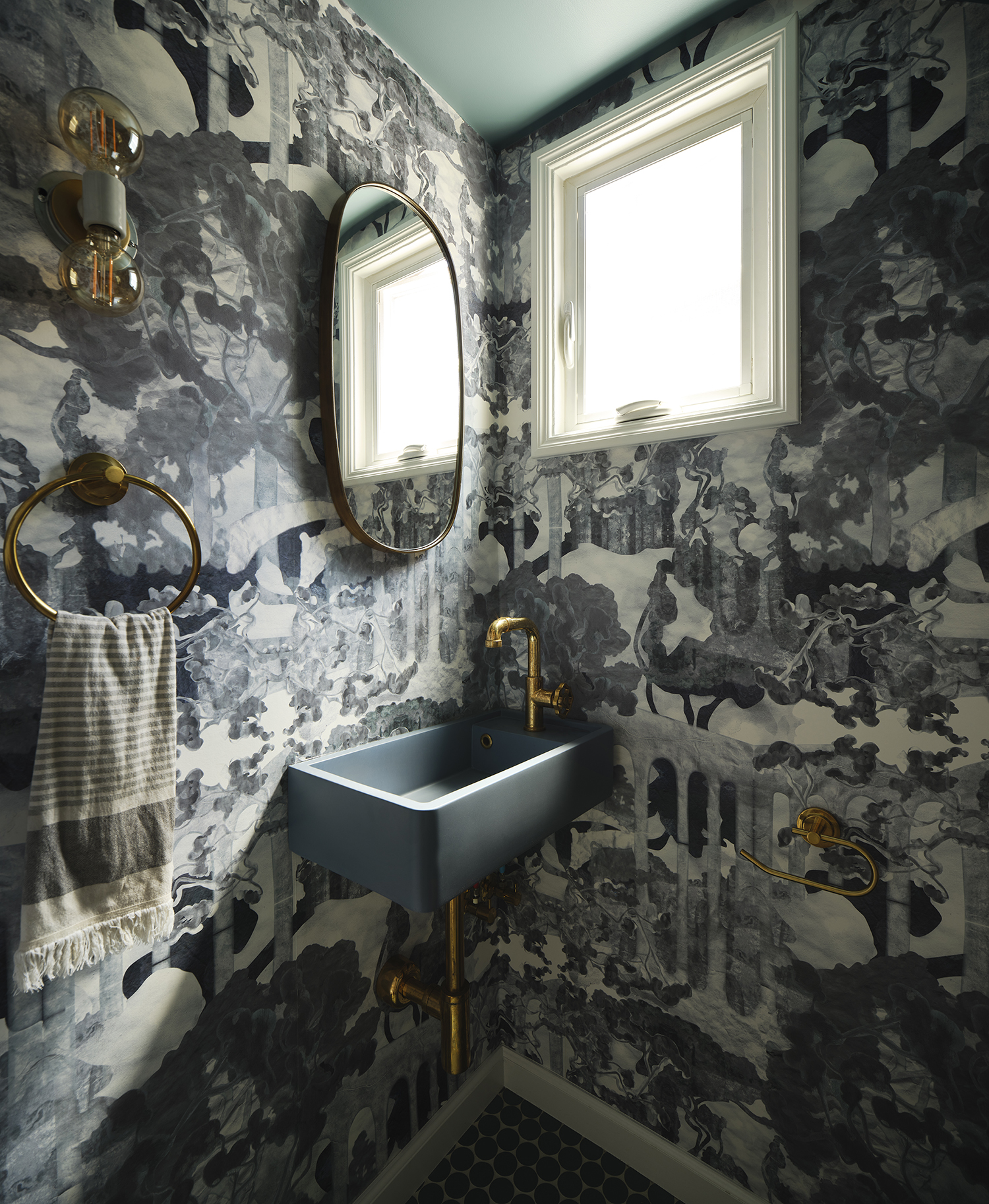 teal and navy maximalist bathroom with presido wallpaer, navy sink and curved pill mirror