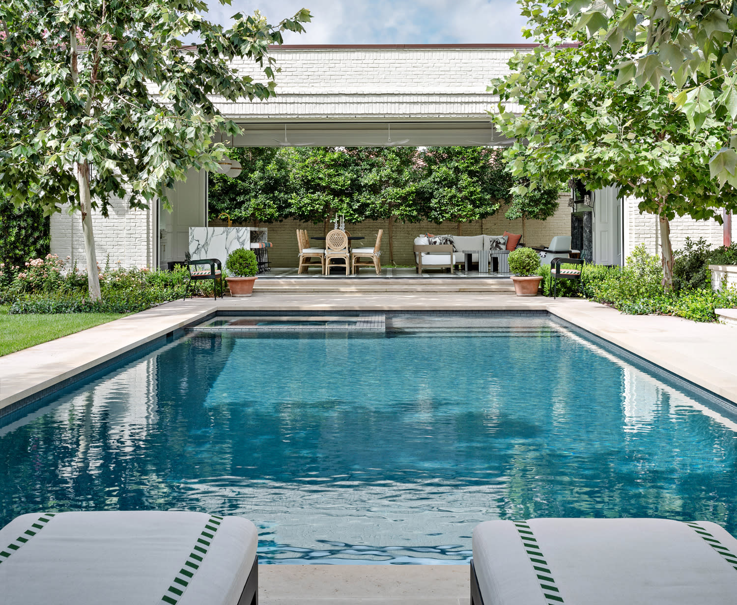 A poolside scene featuring a lounge chair and a small table beside the water.