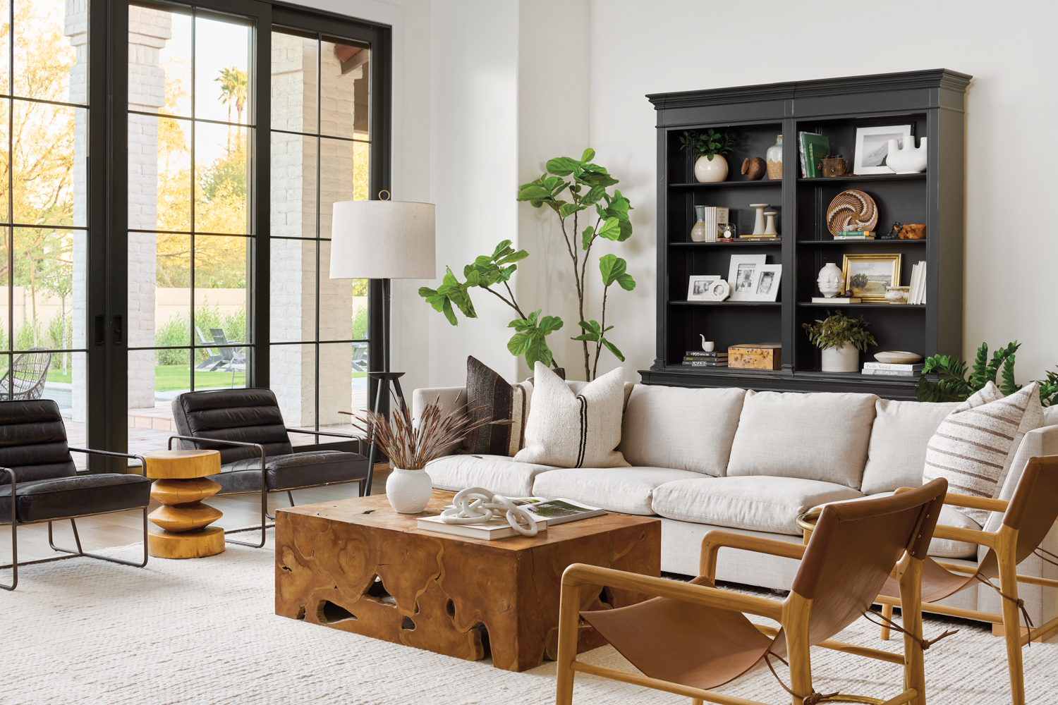 living room with a tan couch, black armchairs, sling chairs, wood coffee table and black bookcase