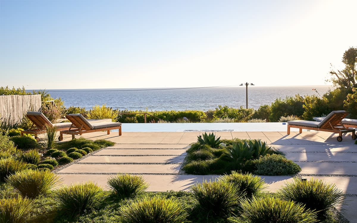 A scenic view of the ocean from a patio area, showcasing blue waters and a clear sky.
