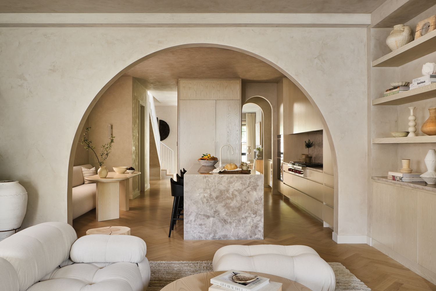 Archway leads into a kitchen with a honed white-crystal quartzite island and a breakfast nook