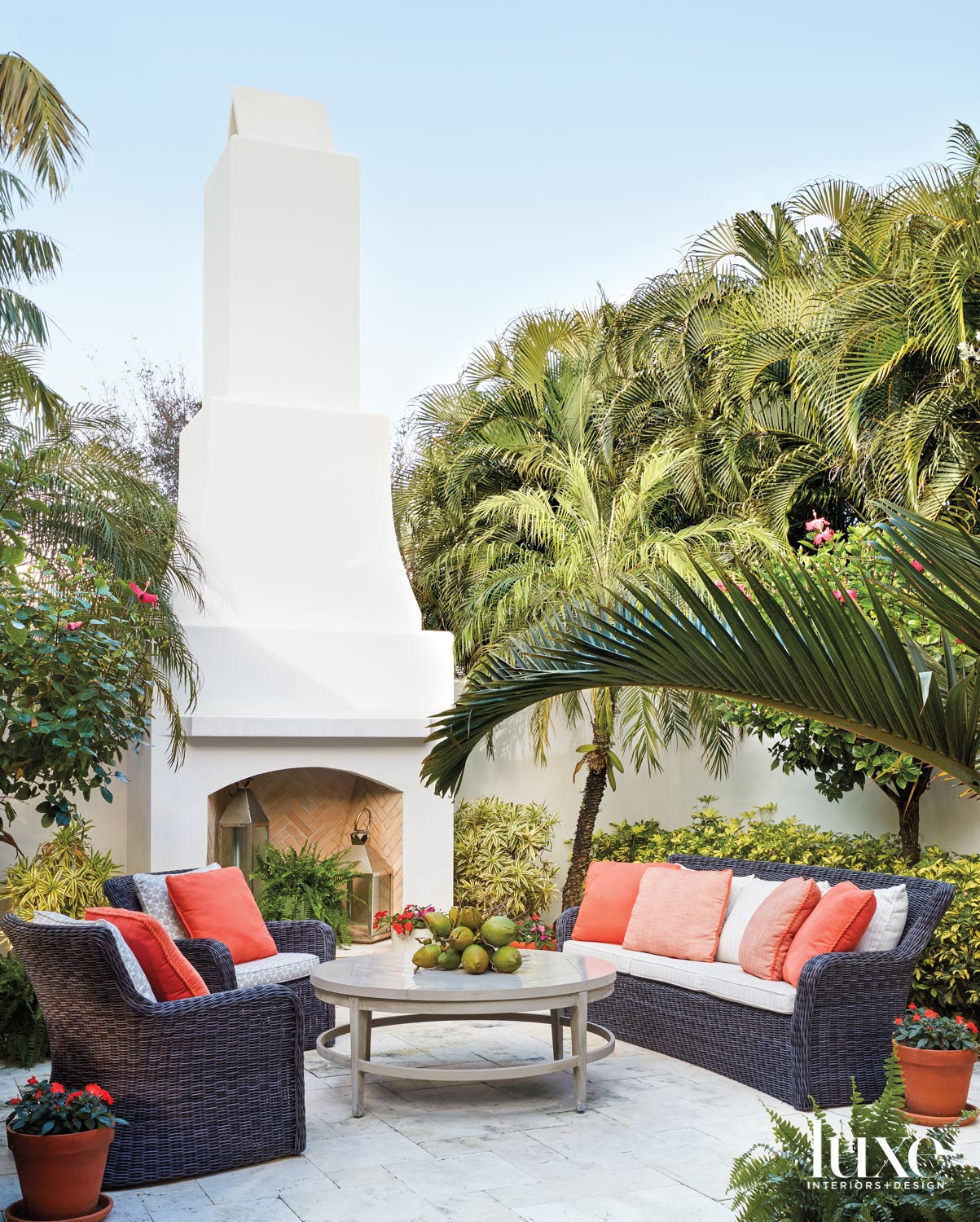 outdoor fire pit space with sofa, armchairs, coffee table and coral pillows