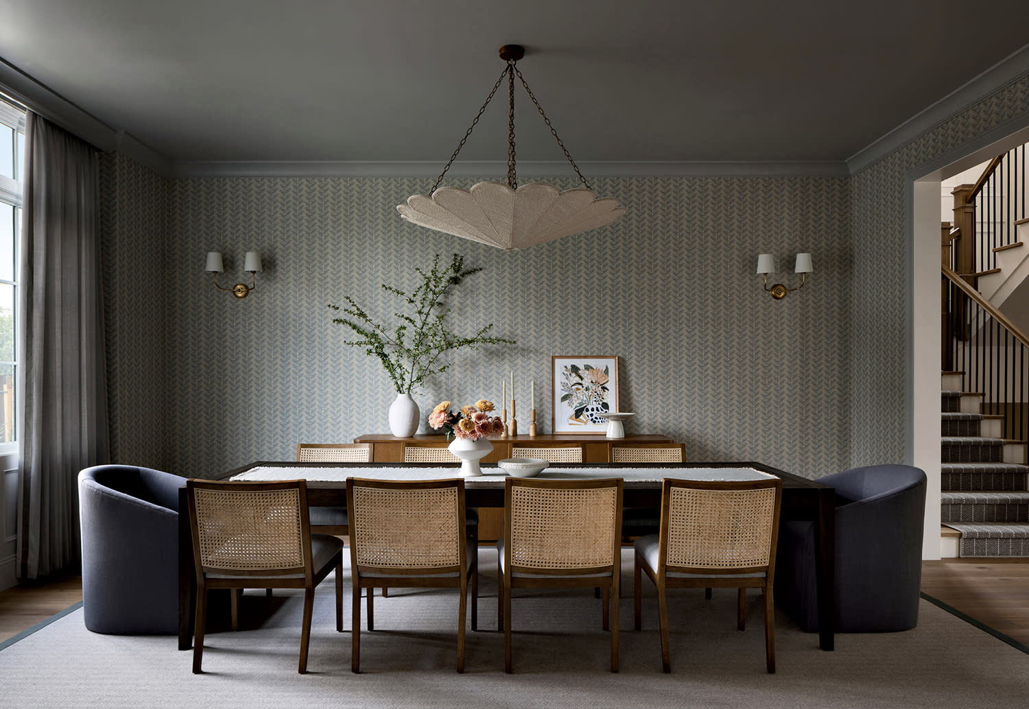 dining room with a green floral theme wallcovering and a petal-like chandelier above the table
