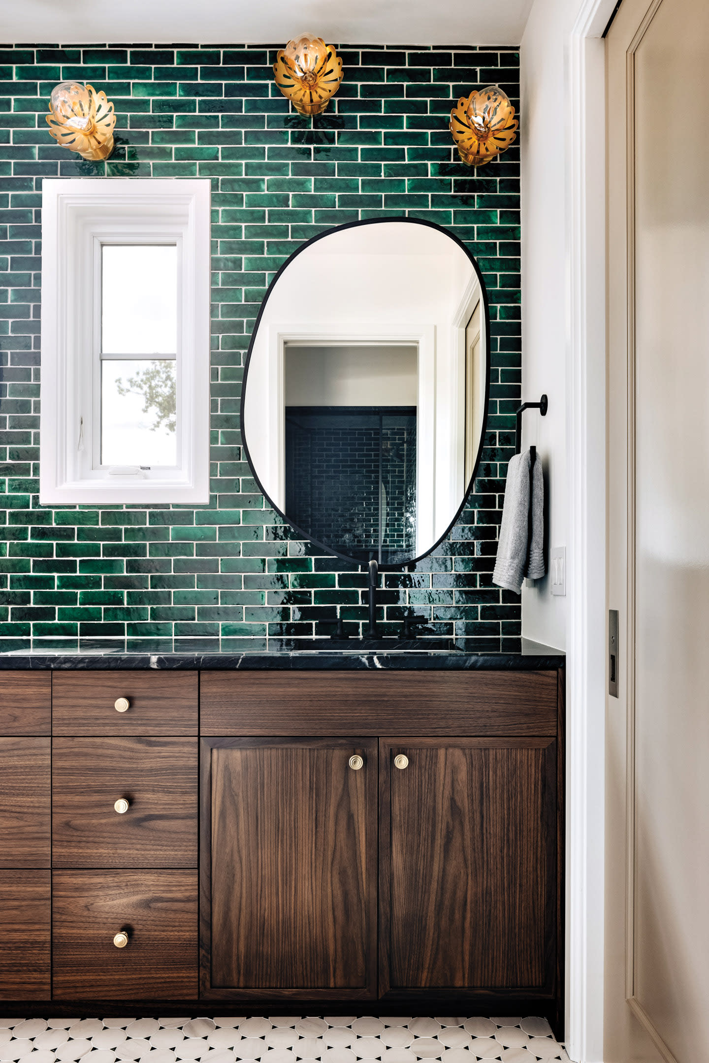 rich wood vanity with brass knobs in a green tile bathroom