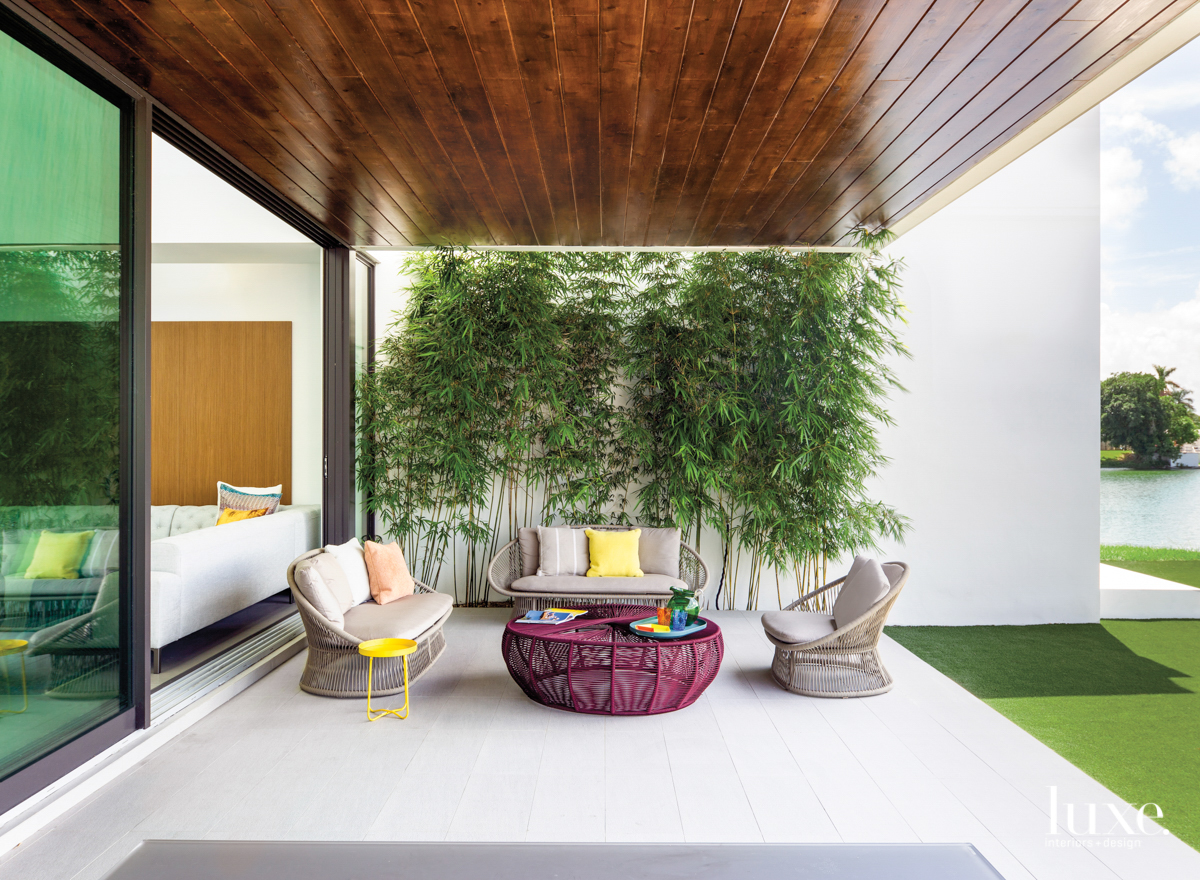 modern miami loggia with bamboo wall, gray furnishings and purple coffee table