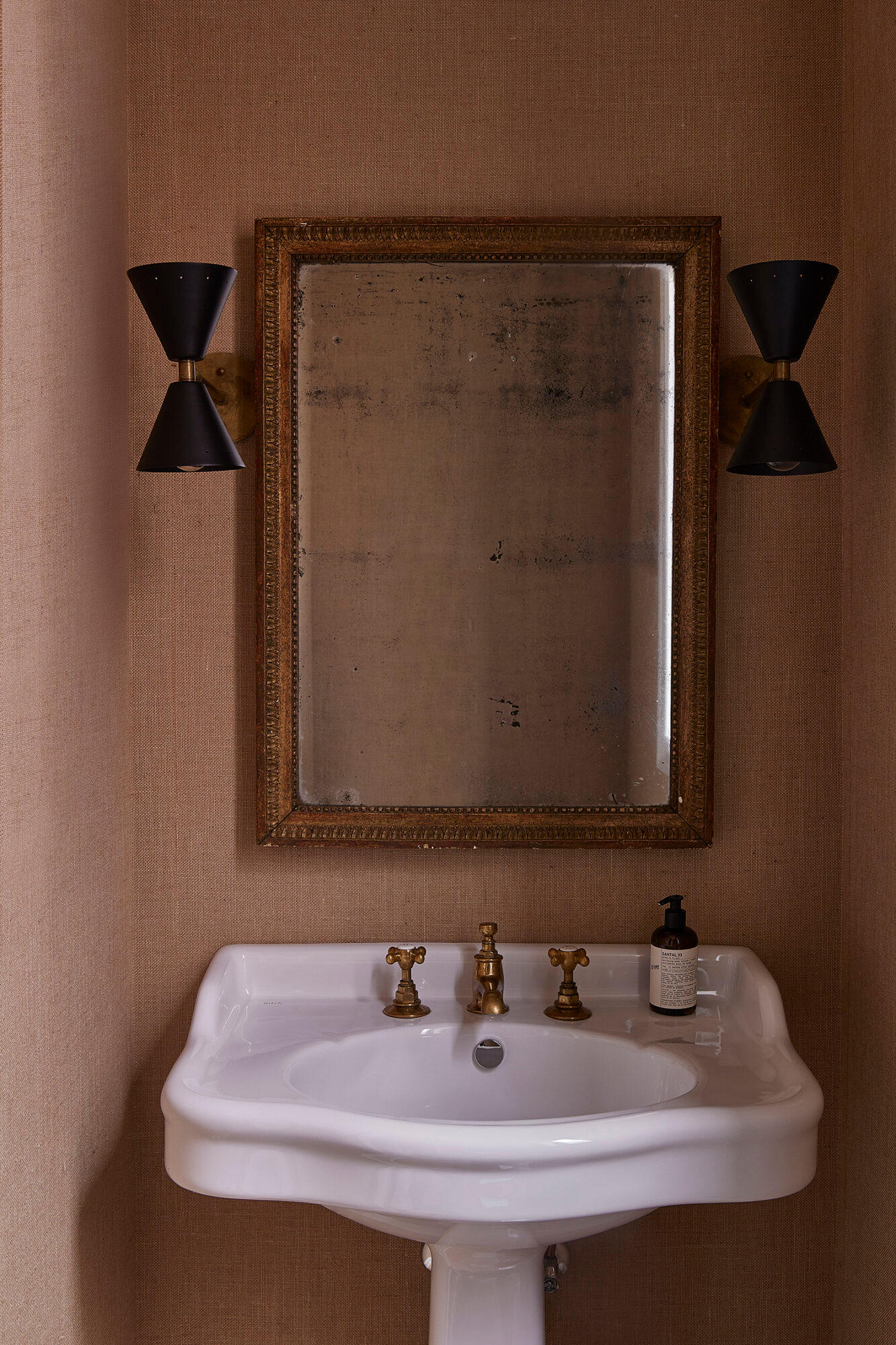 bathroom featuring a pedestal link and black sconces