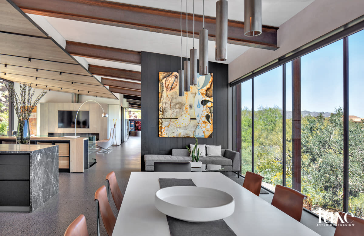An dining space that opens to the kitchen and living areas. An abstract painting hangs on the wall.