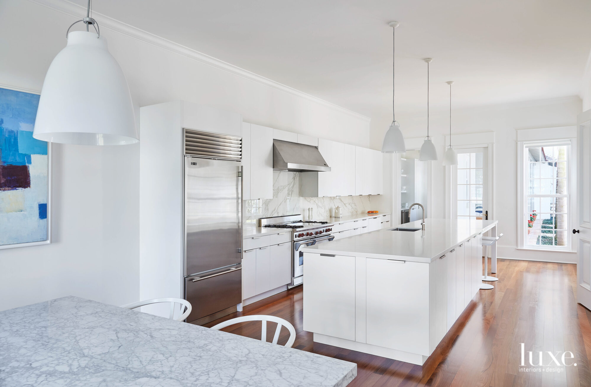 Kitchen with white cabinetry and marble backsplash.