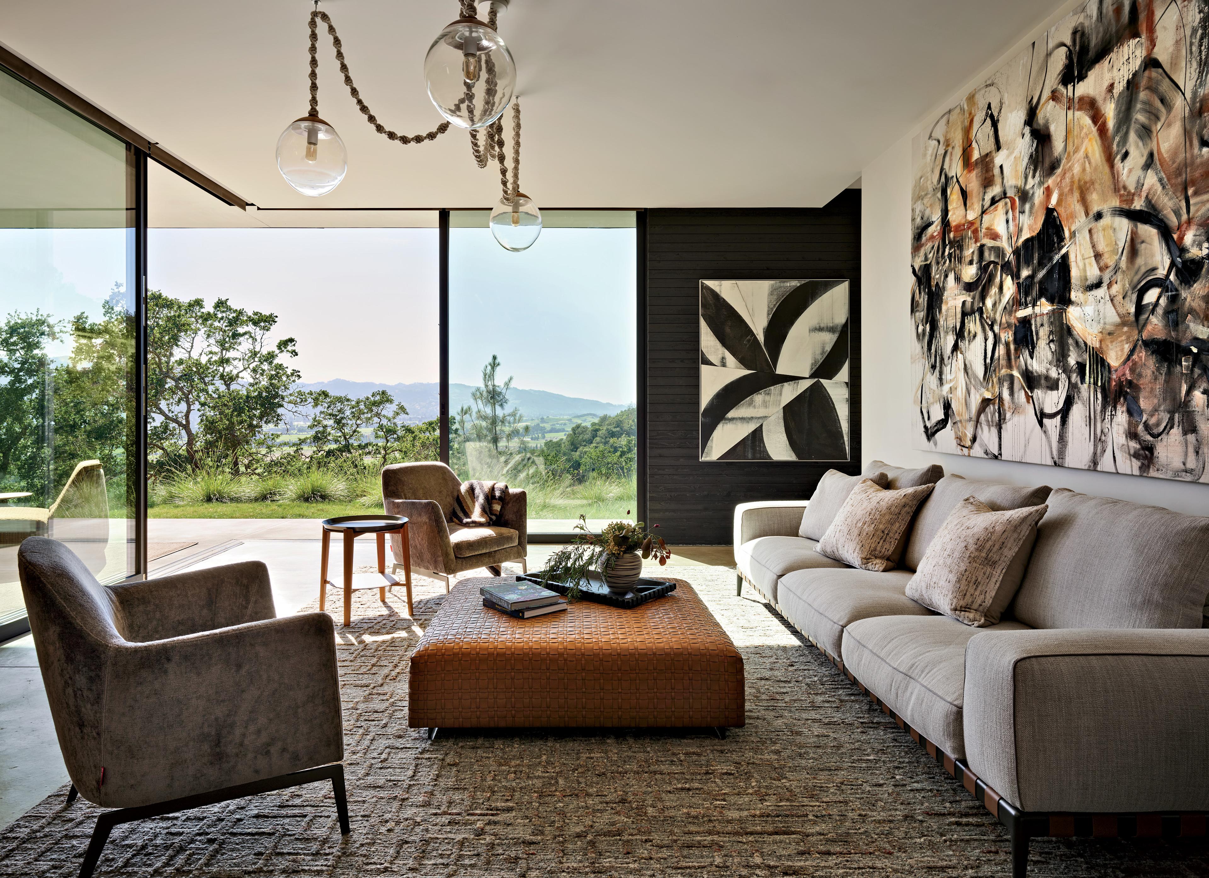 A living room decorated with sofa, armchairs and a coffee table with artwork on the walls.