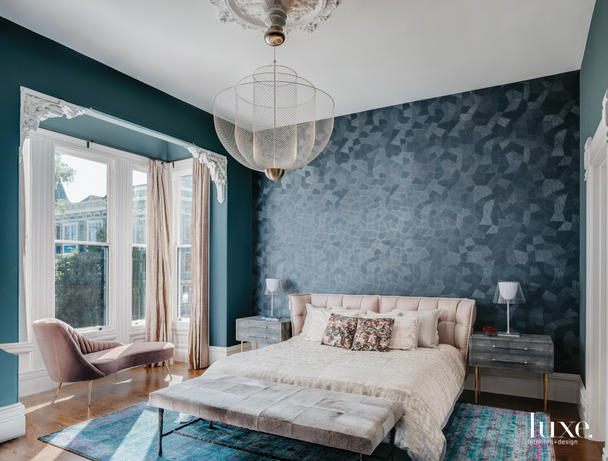 master bedroom with blue wallcovering and blue rug and bench in front of window