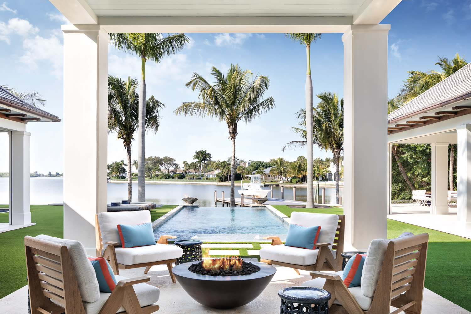 covered loggia with four armchairs, fire pit and view of pool and waterway