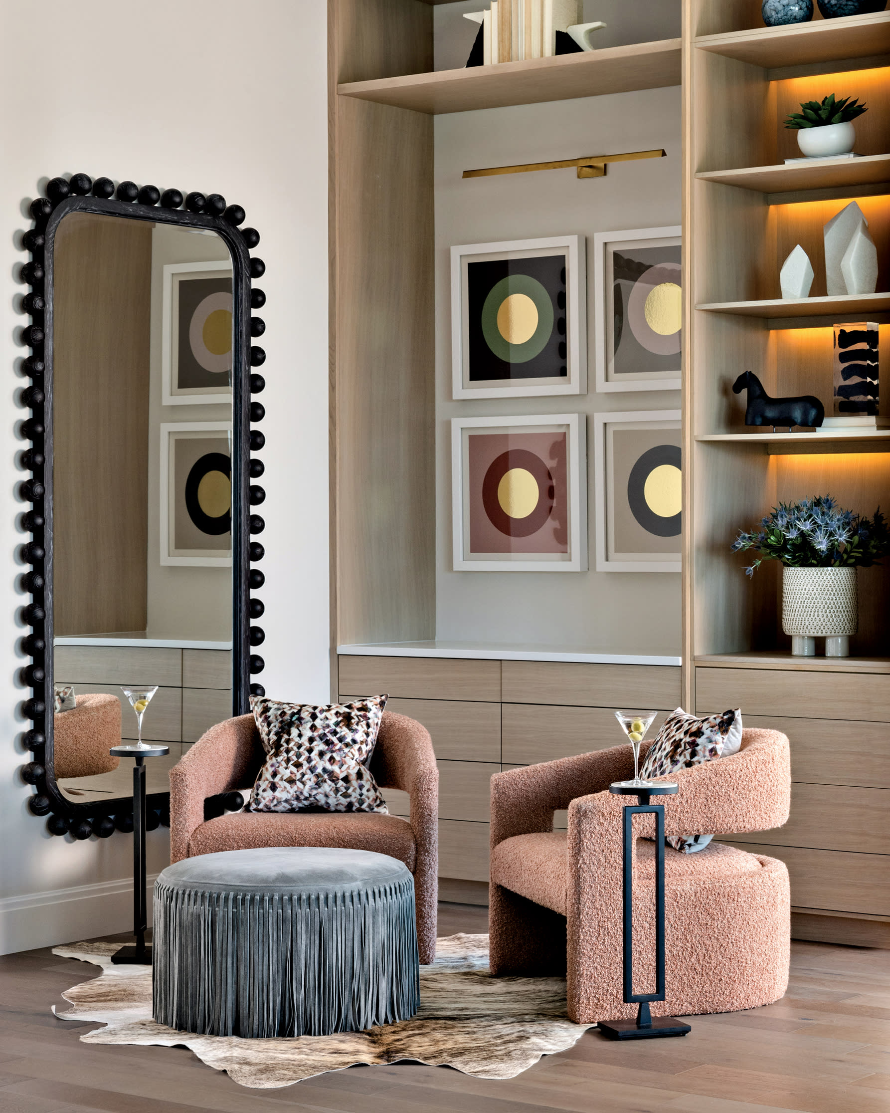 modern lounge with pink boucle armchairs and a blue fringe stool