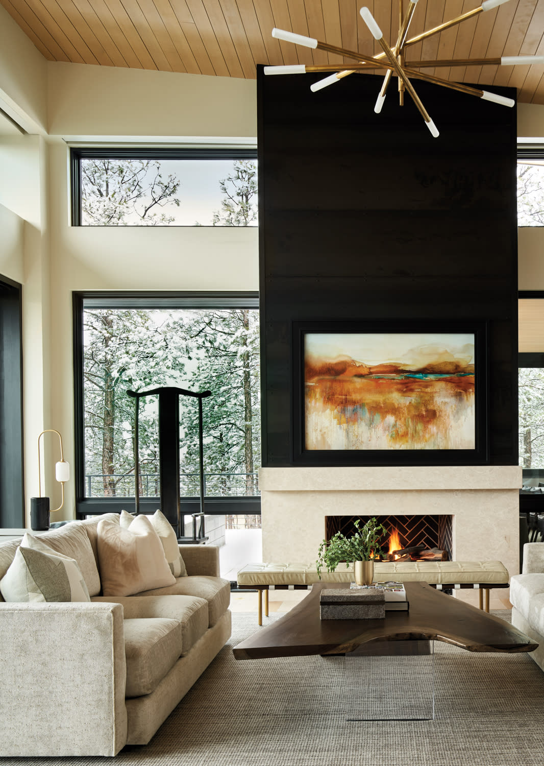 stone-and-steel fireplace in great room flanked by large windows