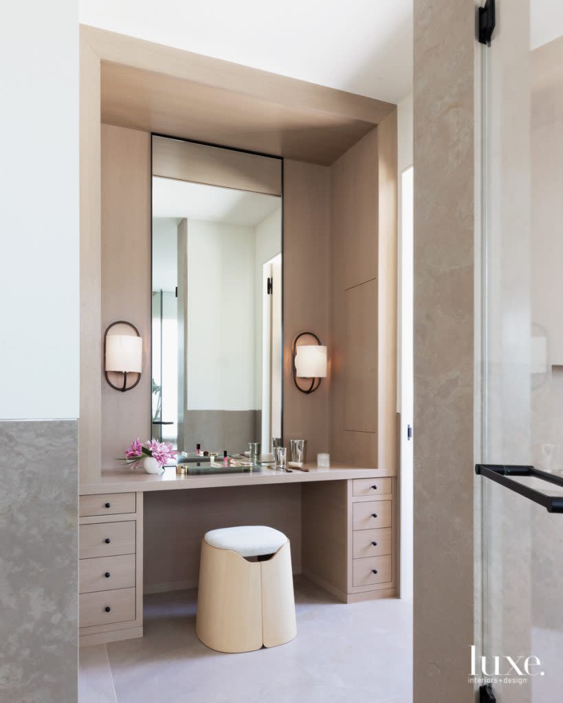 The serene master bathroom features a makeup vanity for the wife. A Joa stool by Studio Briand & Berthereau for Ligne Roset sits in front of a mirror flanked by Bit sconces by Michael Amato for Urban Electric.