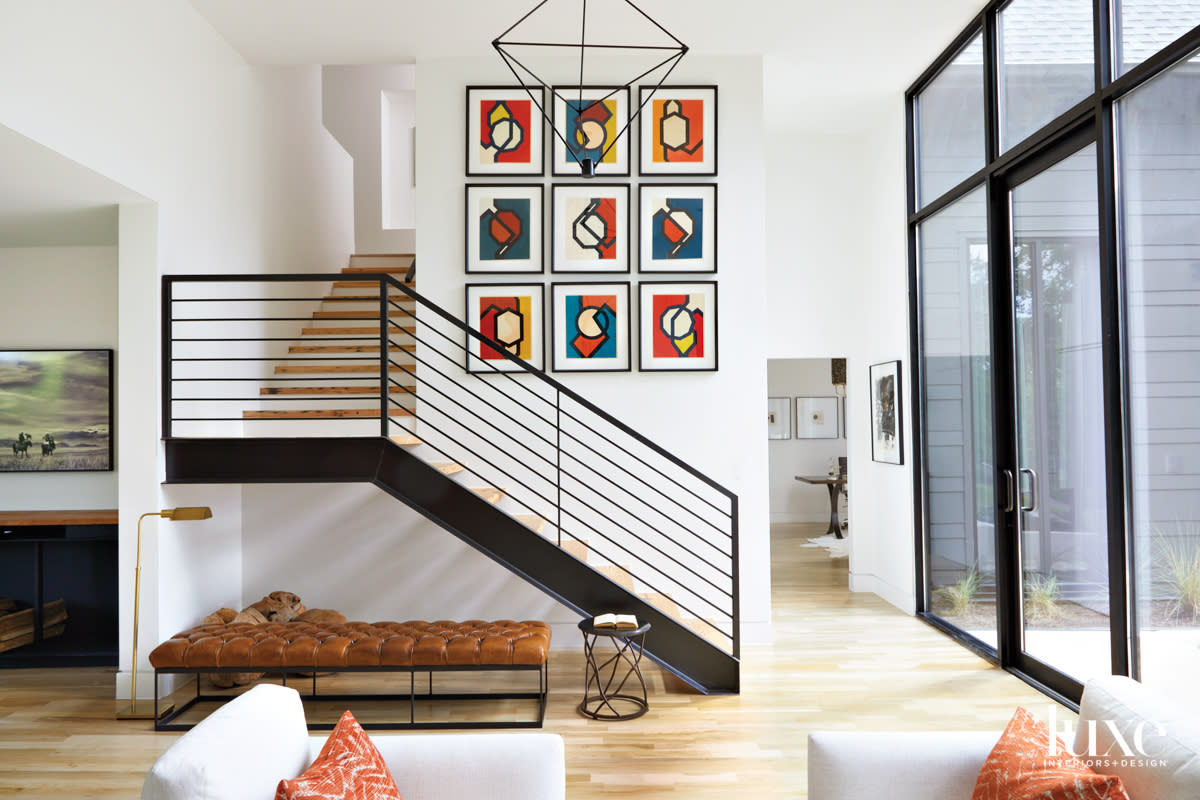 Modern metal staircase with collage of colorful prints on wall, plus modern ceiling pendant