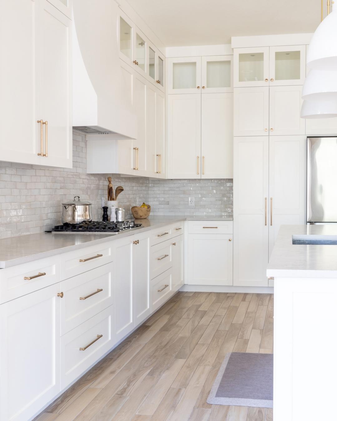 a kitchen with white cabinets and wood floors