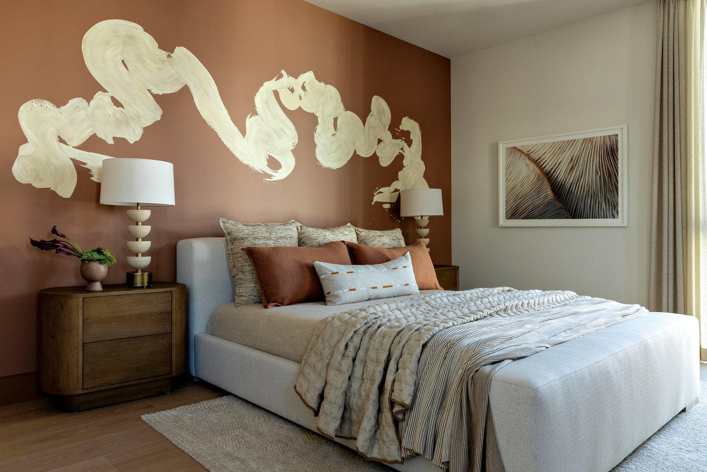 Bedroom styled with layered luxury bedding including quilt, coverlet, and decorative pillows in neutral tones.