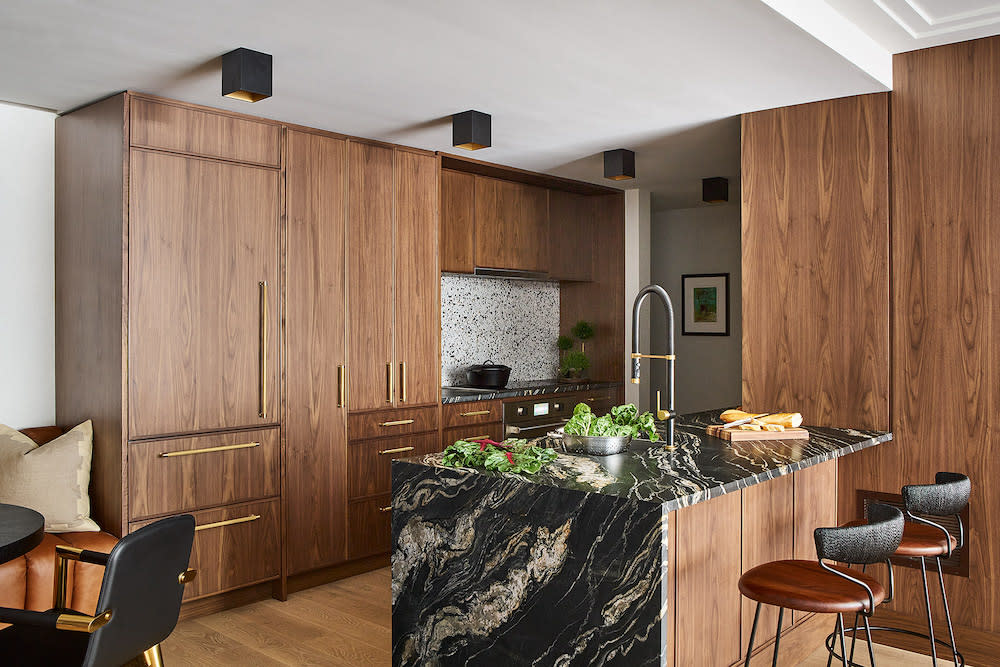 Walnut cabinets, terrazzo backsplash, brass hardware, black marble waterfall island.