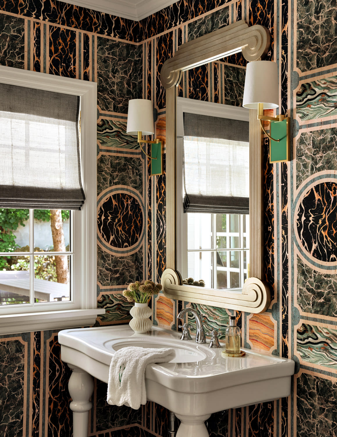 Gucci marble print wallpaper lines the walls of this powder room with a silver antique mirror