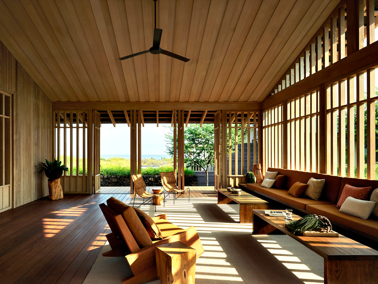 A cozy living/sun room featuring wooden floors and a ceiling fan, creating a warm and inviting atmosphere.