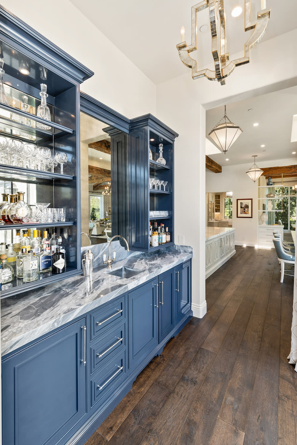 Contemporary residential wet bar featuring blue cabinets and marble countertop.