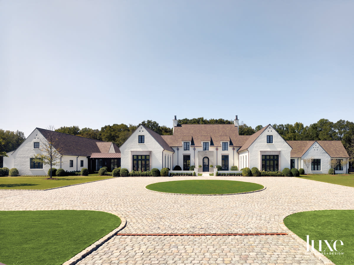 Motor court and facade of a large and stately home in white brick