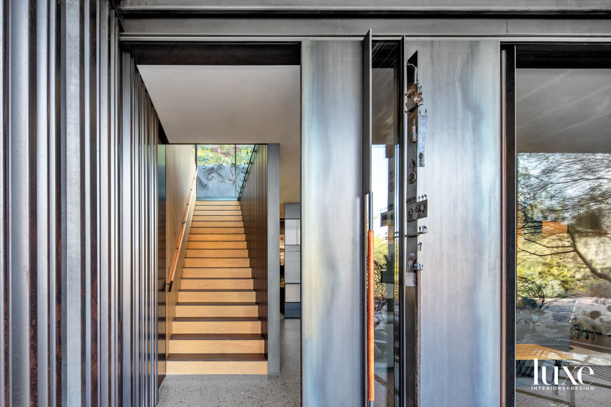 An entryway with terrazzo floors and wood stairs.