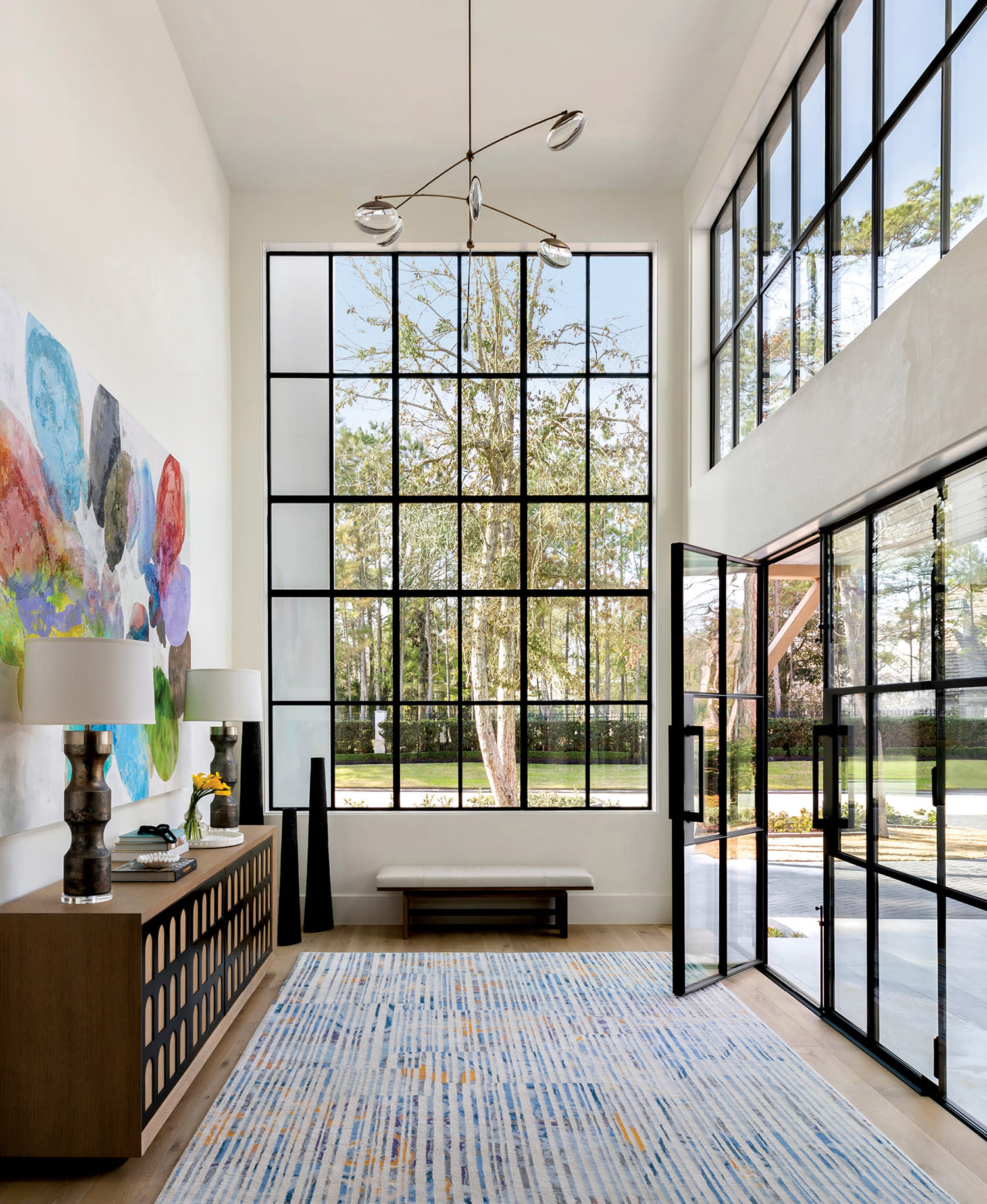 foyer with double-height steel-and-glass windows and doors and a hand-blown chandelier