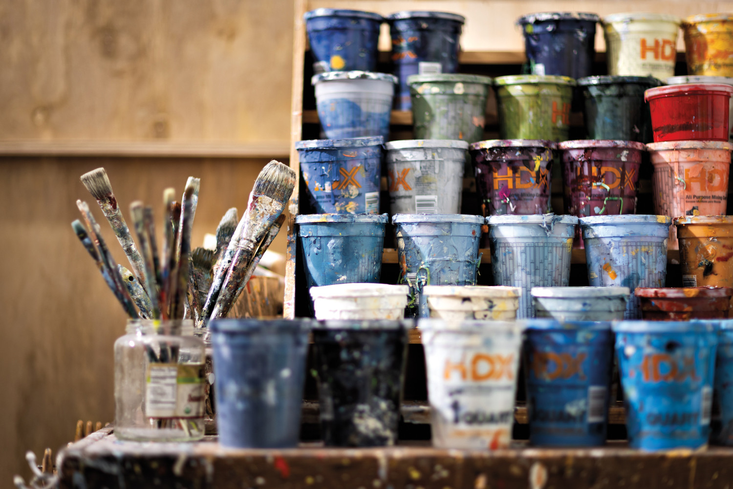 Rows of paint and a cup full of paintbrushes.