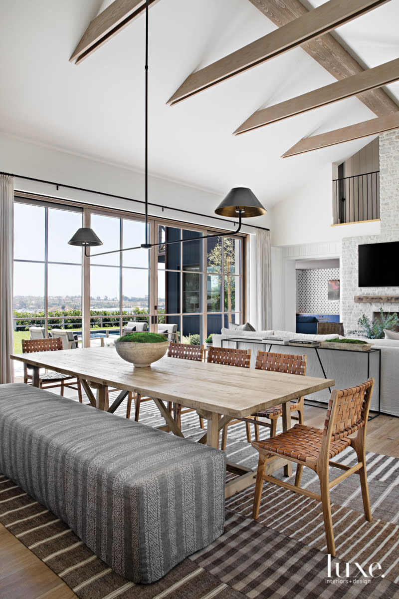 dining table with bench and wood chairs in front of windows of walls