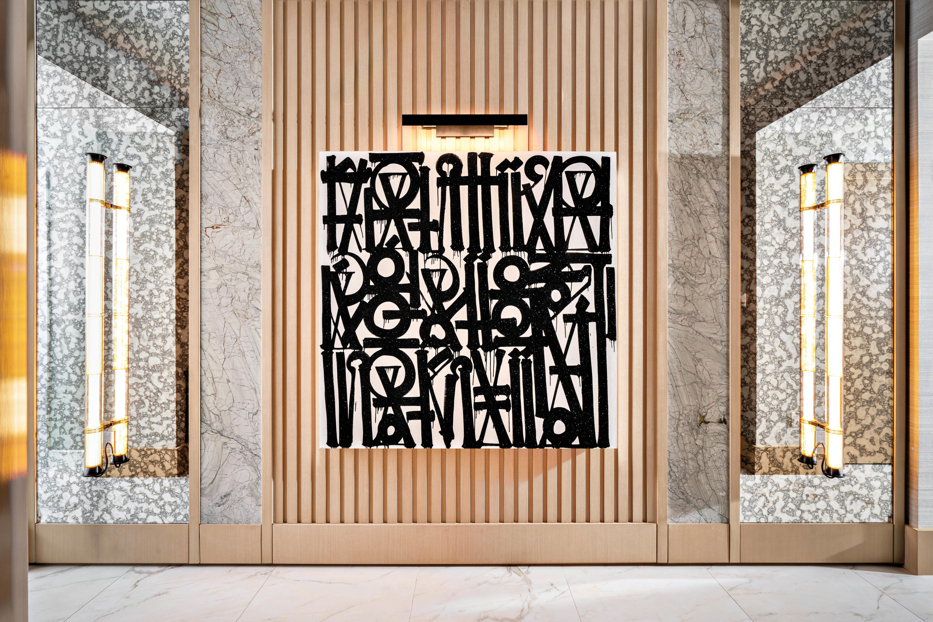 foyer with slatted wood panelling and a Retna artwork resting upon it