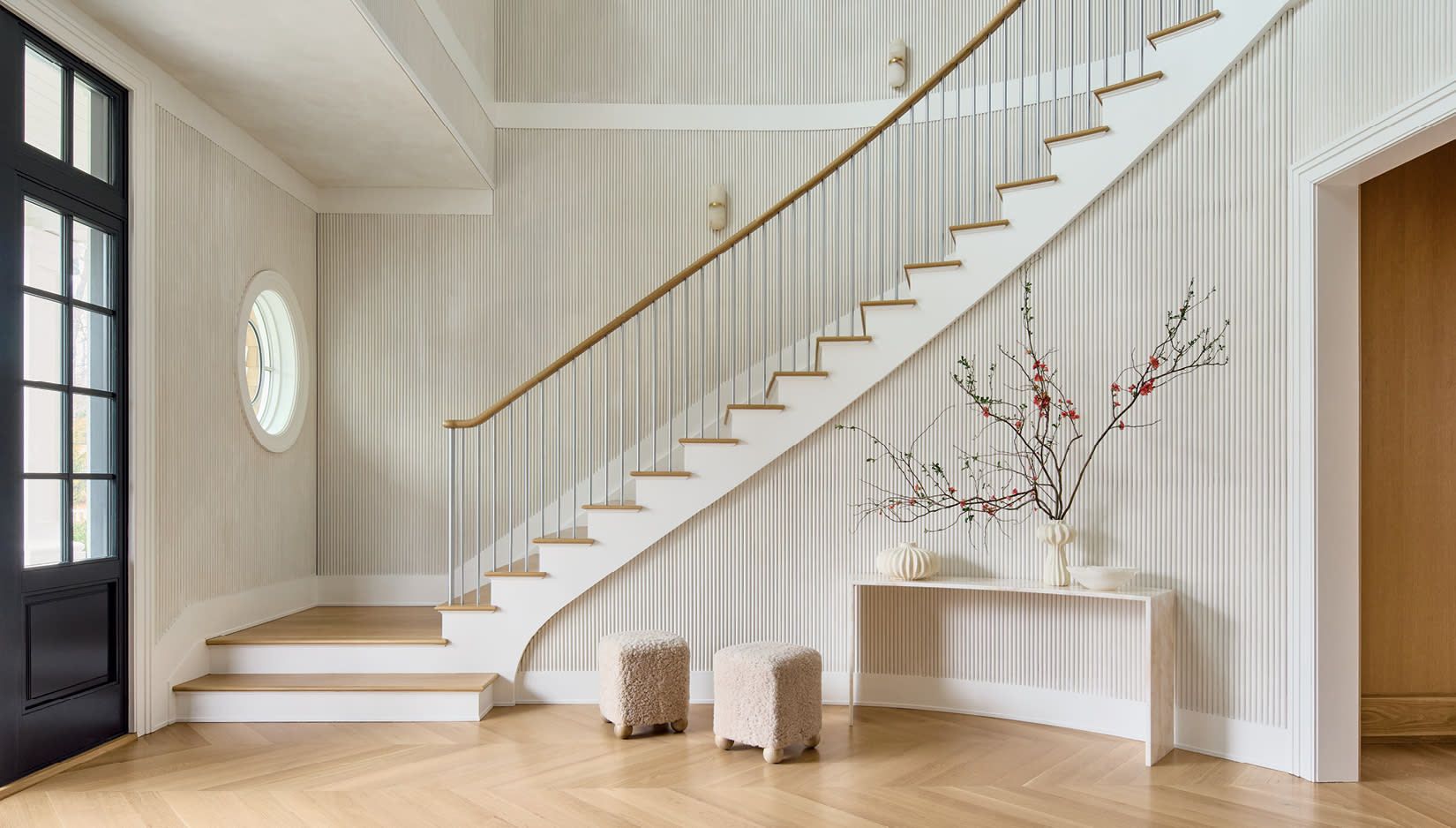 entryway of a shingle-style home with fluted paneling along the staircase wall